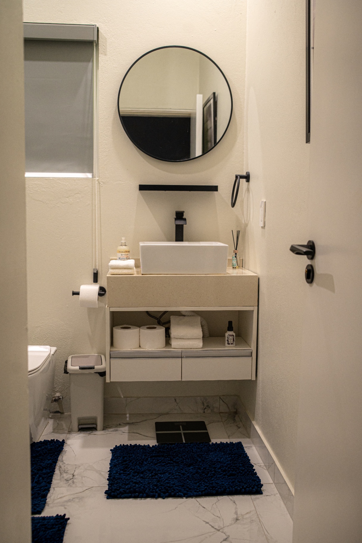 Apartment 2 bathroom with round mirror and vessel sink
